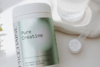 Container of Prohaine Pure Creatine on a light surface with a scoop and transparent container.